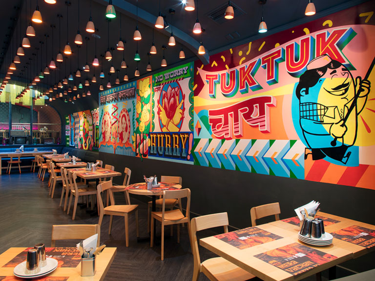Vibrant restaurant interior design. Large painted interior wall at Tuk Tuk Glasgow, inspired by Indian street art.